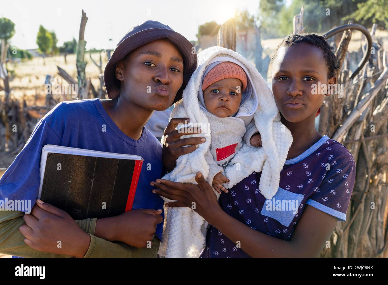 villaggio, ragazzi della scuola africana con un bambino appena nato e libri scolastici in mano Foto Stock