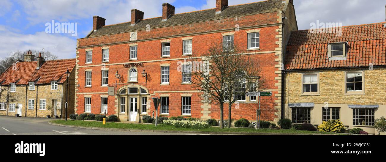 Spring Daffodils intorno agli edifici di Folkingham Village Green; Lincolnshire; Inghilterra, Regno Unito Foto Stock