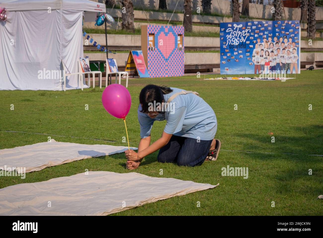 Un giovane attivista thailandese si vede sistemare un pallone a terra, insieme a un'immagine di gruppo di persone ancora detenute in carcere per diverse opinioni politiche, durante il Festival di Amnesty per San Valentino, nella piazza pubblica. 23 persone appartenenti alle organizzazioni di amnistia, insieme a centinaia di attivisti, volontari e persone comuni, si sono riunite per chiedere la fine del processo contro le persone per l'espressione politica, per ripristinare i loro diritti e la loro libertà e per liberare dalle carceri persone con differenze politiche. (Foto di Nathalie Jamois/SOPA Images/Sipa USA) Foto Stock