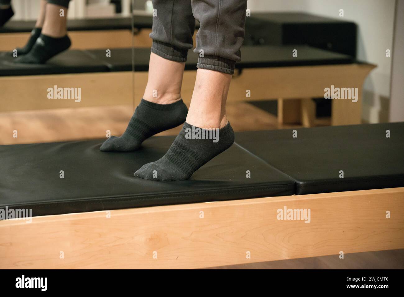 Primo piano dell'allenamento delle gambe sul letto del riformatore. Donna caucasica Foto Stock