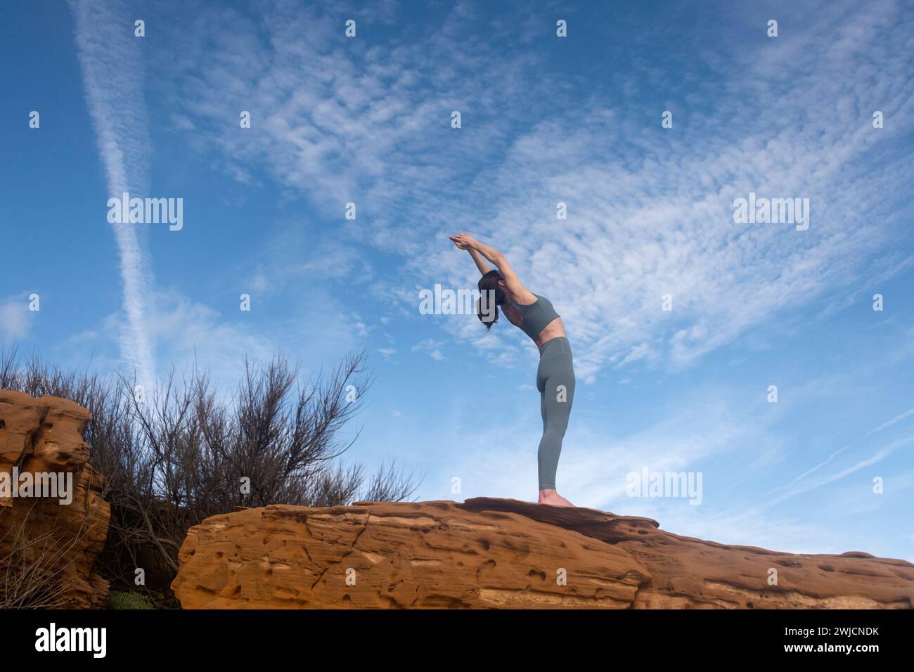donna in piedi su rocce che fa un esercizio di backbend, fuori. posa yoga. Foto Stock