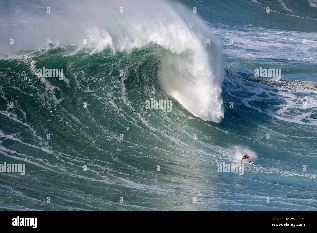 Un surfista cavalca un'onda che si schianta, Nazare, Portogallo Foto Stock