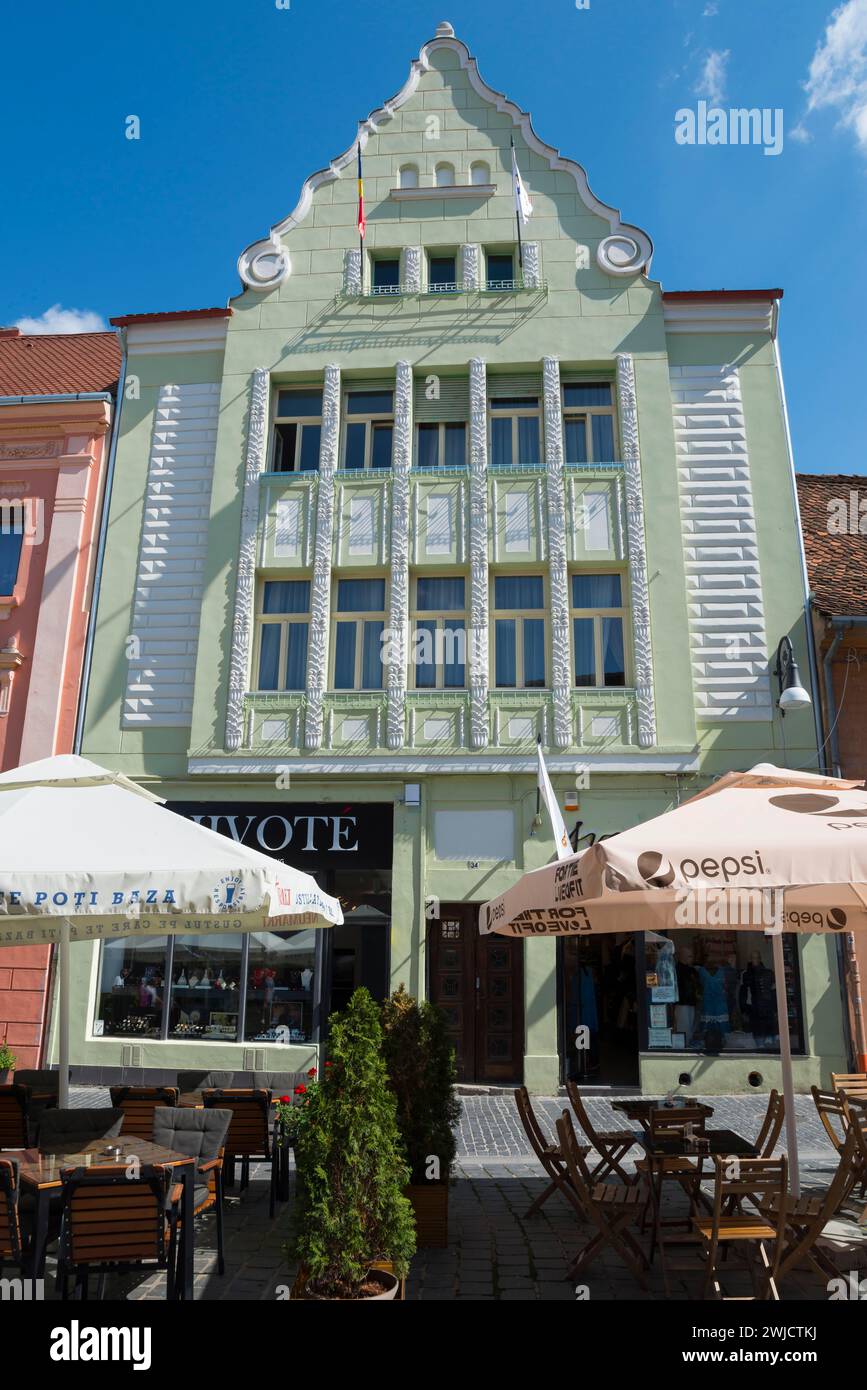 Storico edificio Art Nouveau in verde pastello con caffetteria al piano terra sotto un cielo blu, casa cittadina nel centro storico di Brasov, Brasov Foto Stock