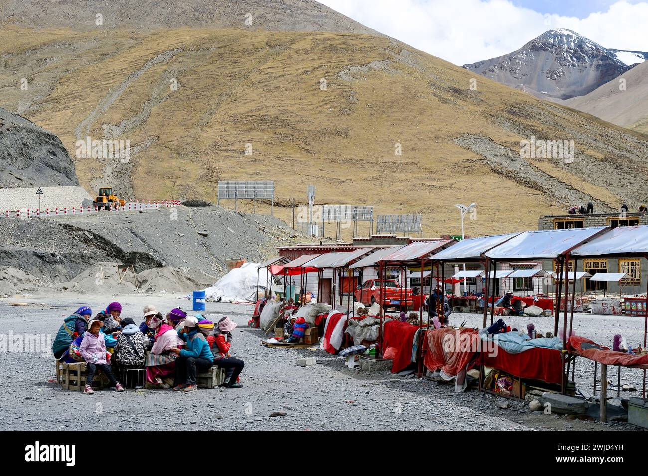 Donne e bambini tibetani fanno una pausa per il pranzo vendendo artigianato e opere d'arte tradizionali in un mercato all'aperto alla periferia di Shigatse. Foto Stock
