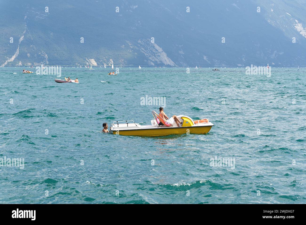 Pedalò con due vacanzieri sul Lago di Garda nei pressi della città italiana di Riva del Garda in estate Foto Stock