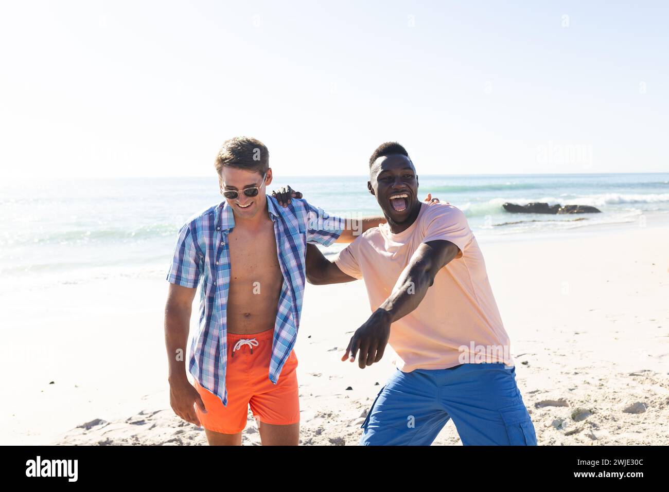 Giovane uomo caucasico e afro-americano godetevi una giornata di sole sulla spiaggia con spazio fotocopie Foto Stock
