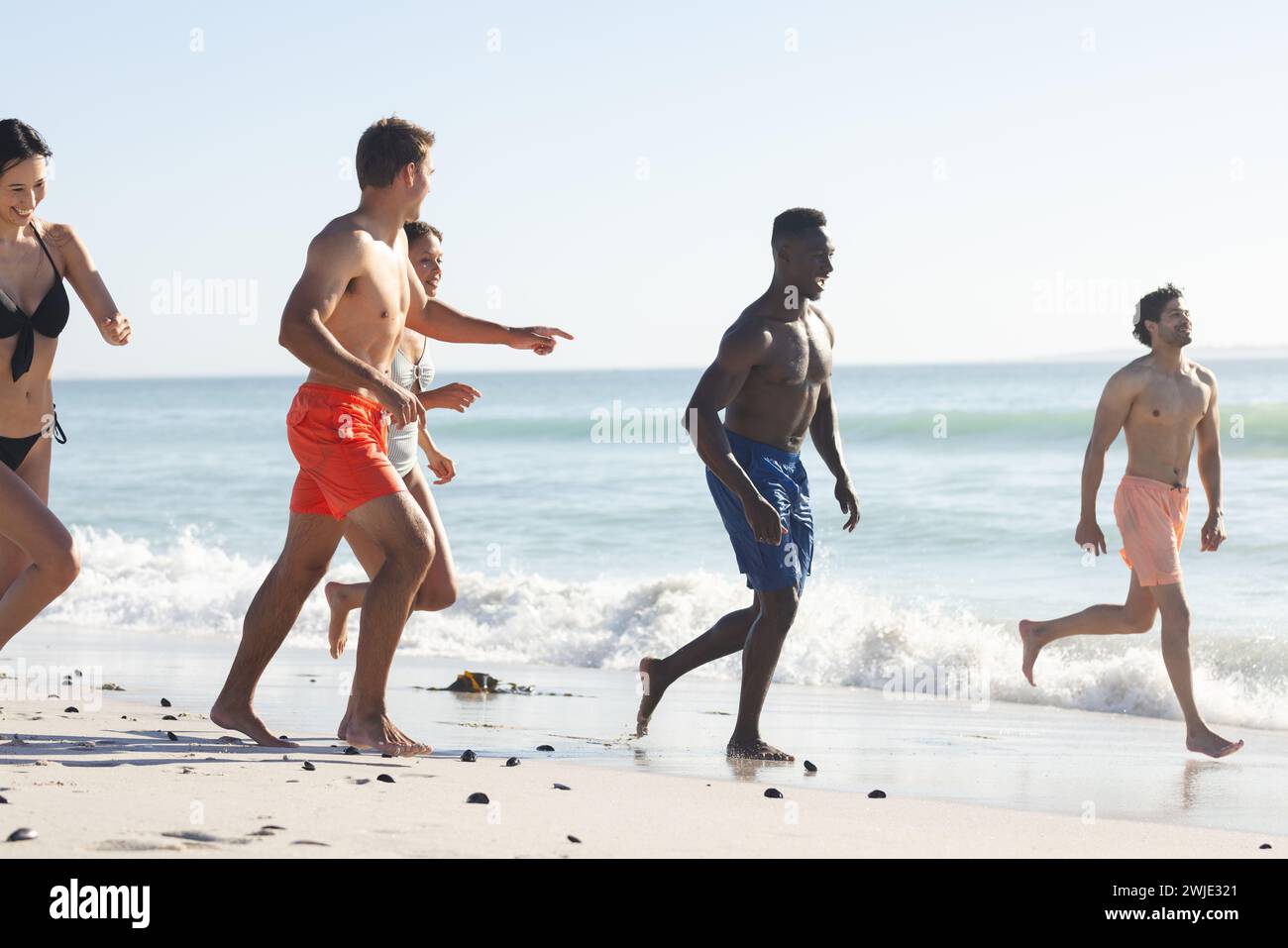 Amici diversi si divertono a correre sulla spiaggia Foto Stock
