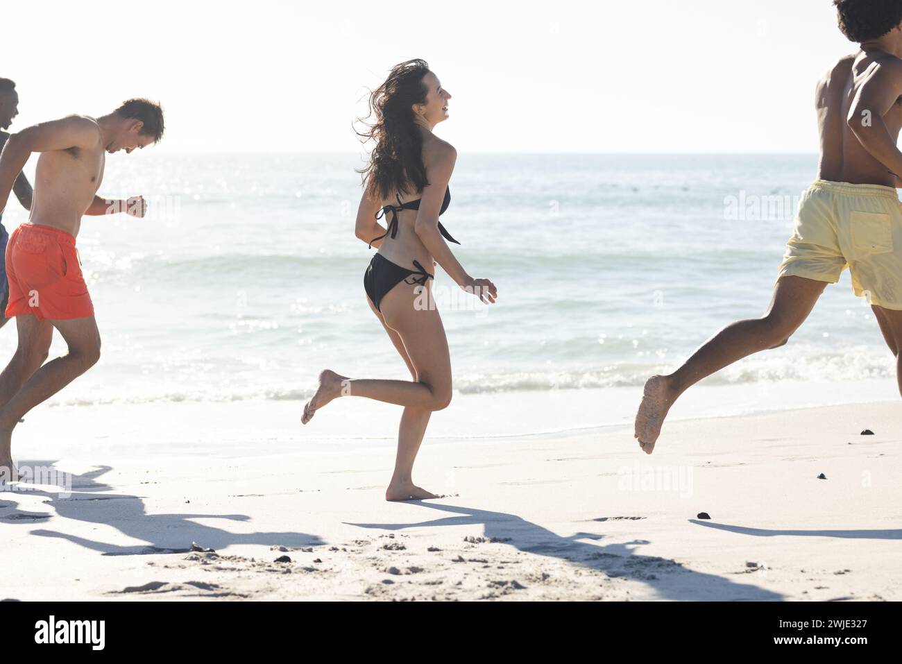 Amici diversi si godono una corsa vivace sulla spiaggia Foto Stock