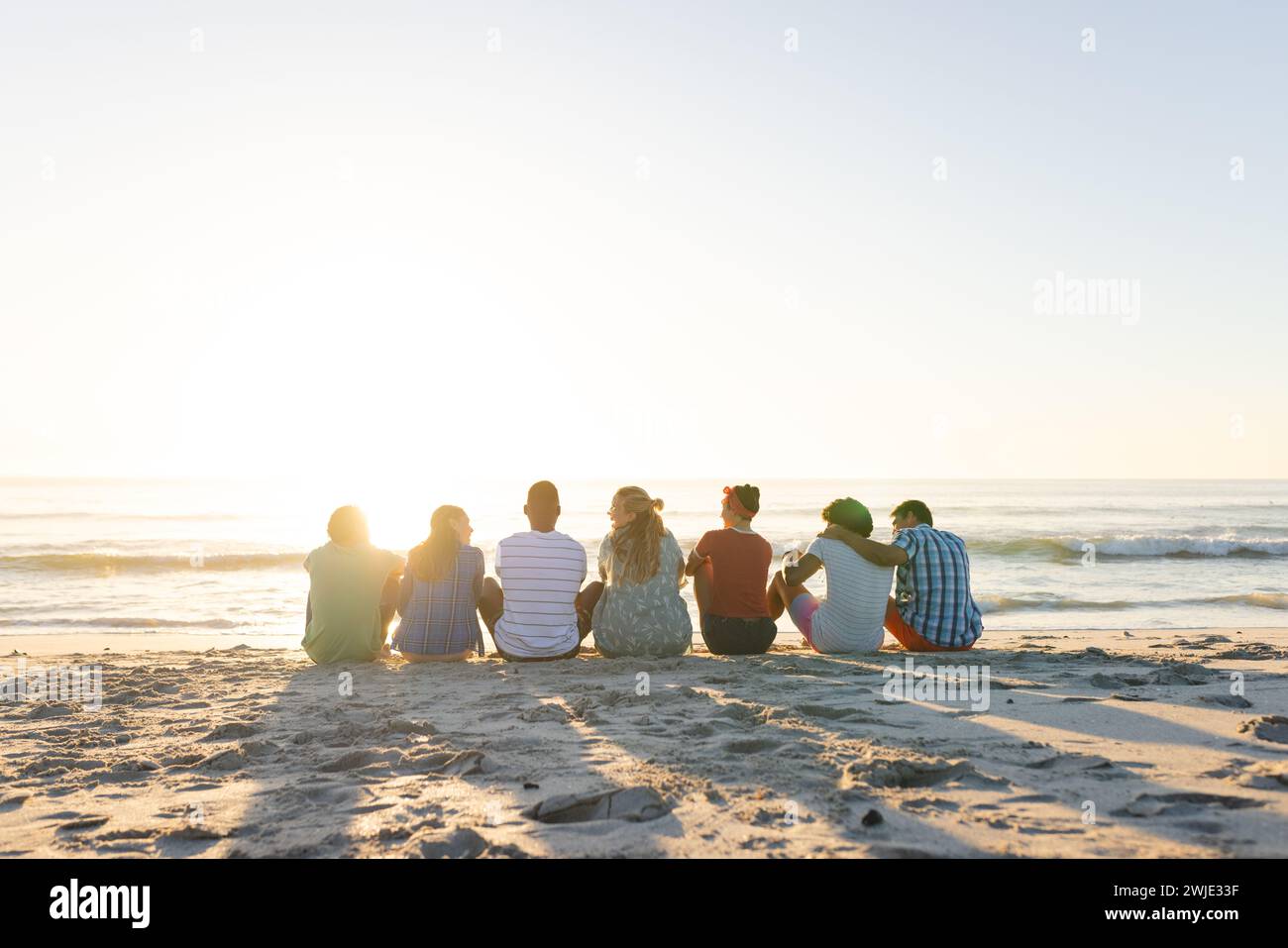 Diversi gruppi di amici si godono un tramonto sulla spiaggia, con spazio per le copie Foto Stock