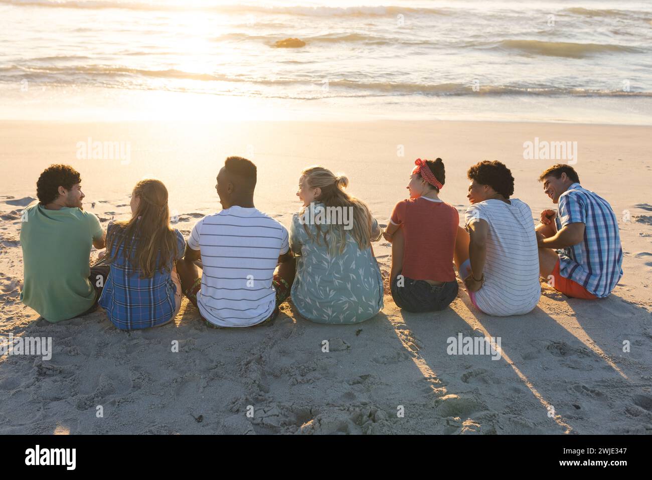 Diversi gruppi di amici si godono un tramonto sulla spiaggia Foto Stock