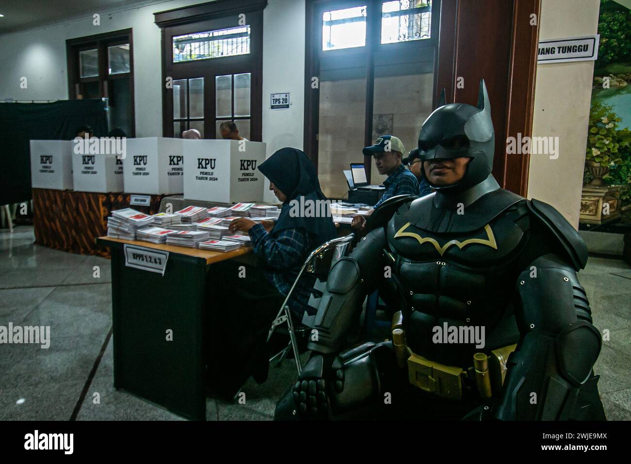 Un funzionario delle elezioni che indossa un costume di Batman lavora durante la presidenza indonesiana in un seggio elettorale a Bogor, Indonesia, il 14 febbraio 2024 Foto Stock