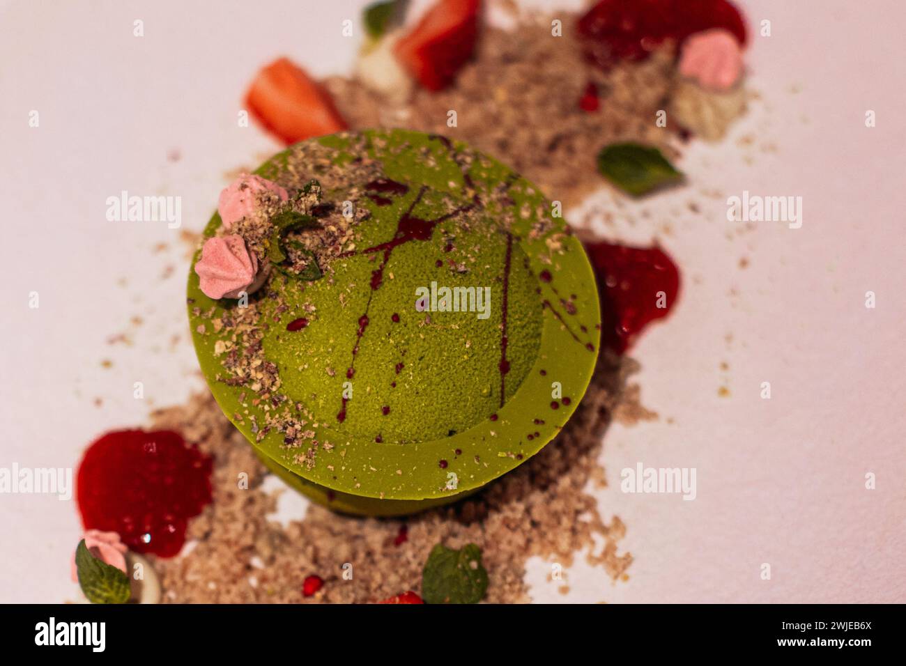 Primo piano: Delizioso dessert al pistacchio dolce con pezzi di fragole fresche, marmellata e biscotti sbriciolati. Vista dall'alto Foto Stock