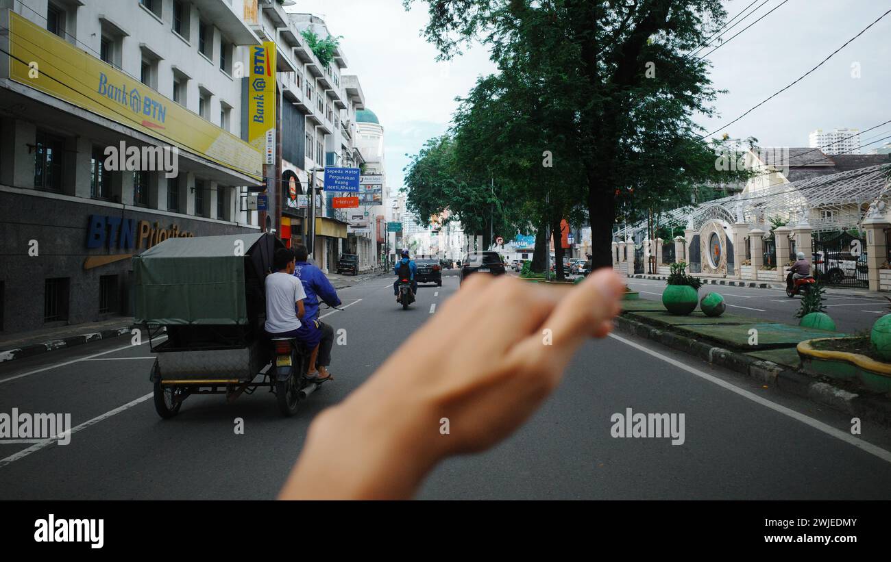 La città di Medan pulsa di vita mentre le persone navigano per le sue strade su vari veicoli, un vivace quadro di mobilità urbana e attività Foto Stock