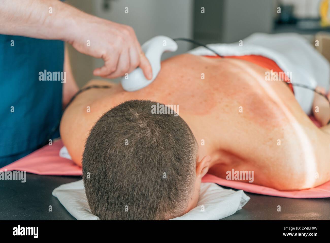 Massaggiatore che fa pressione calda con l'aiuto di moderne apparecchiature elettroniche. Foto Stock