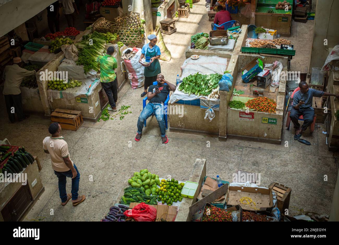 I commercianti di frutta e verdura aspettano clienti all'interno del mercato di Kisutu a Dar es Salaam, Tanzania, nell'Africa orientale Foto Stock