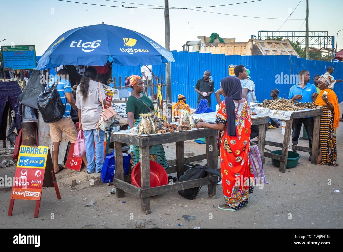La gente vende pesce fritto ai passeggeri che passano attraverso il terminal dei traghetti di Kigamboni a Dar es Salaam, Tanzania Foto Stock