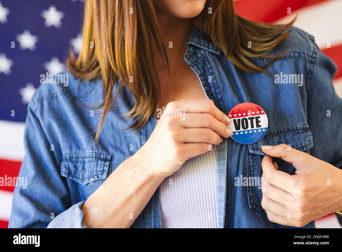 Una donna caucasica di mezza età indossa un badge di voto sulla sua camicia in denim Foto Stock
