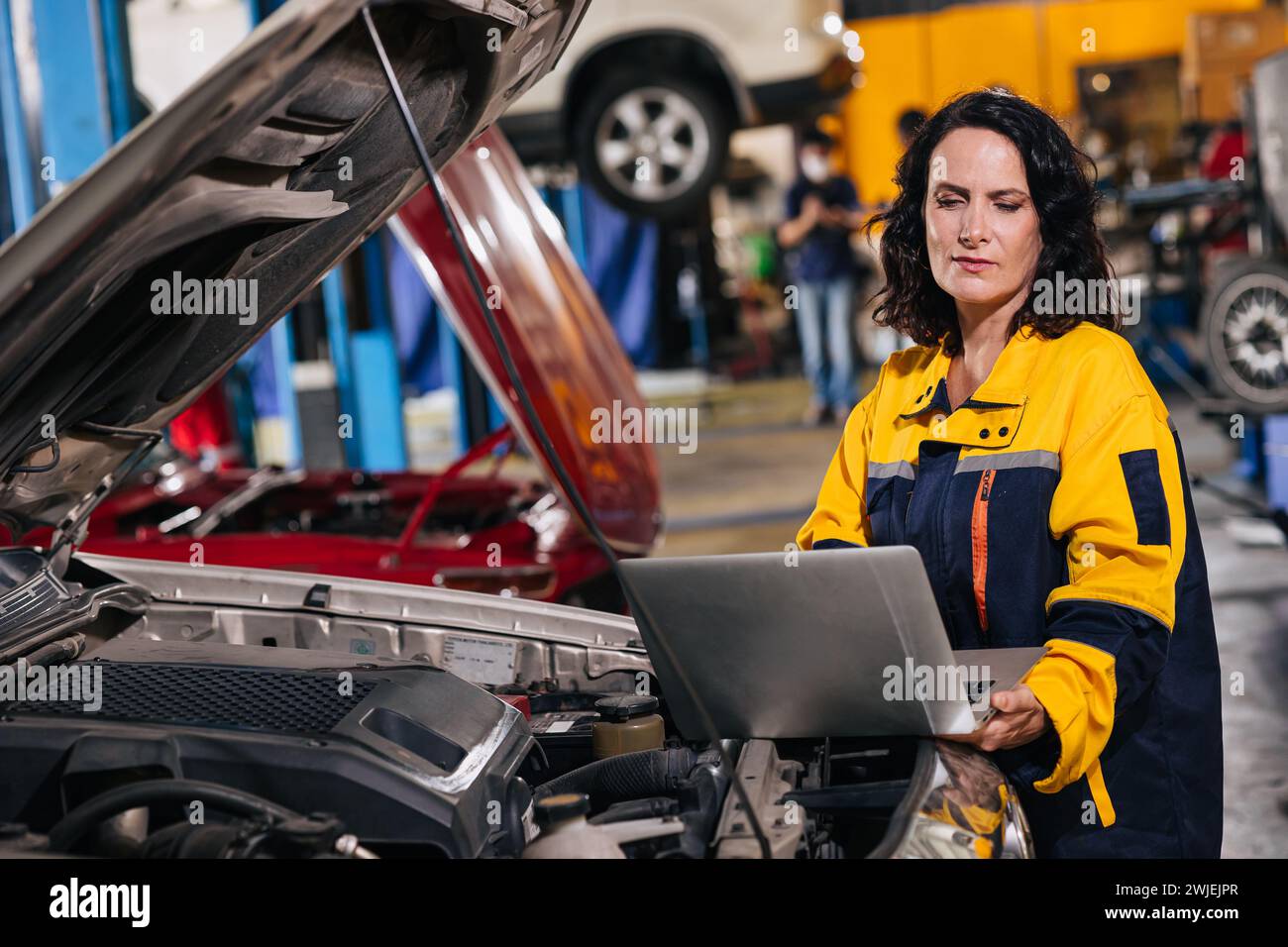 Ingegnere meccanico auto che utilizza computer portatile sintonizzazione ECU analisi diagnosi monitor problema motore in garage auto service Foto Stock