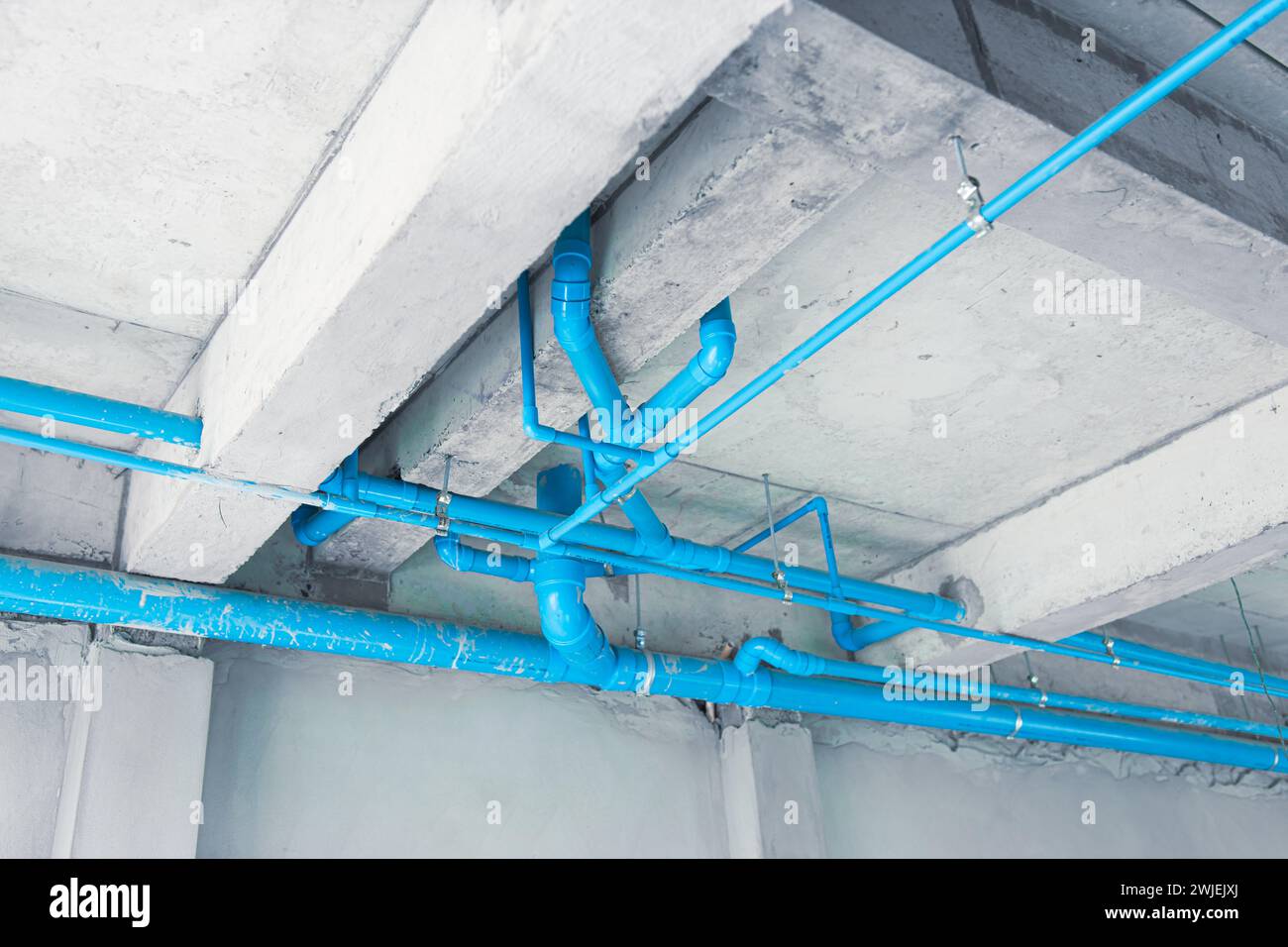 tubo in plastica blu acqua in pvc installato sul tetto del piano terra in un edificio in costruzione Foto Stock