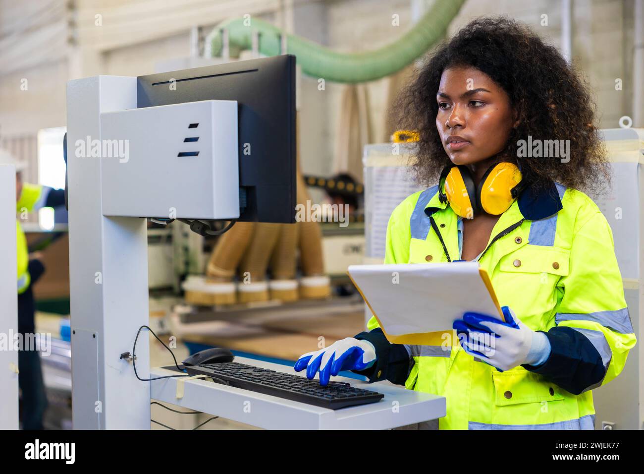 Le lavoratrici nere africane lavorano con l'industria della fabbrica di mobili della taglierina del legno con tuta di sicurezza Foto Stock