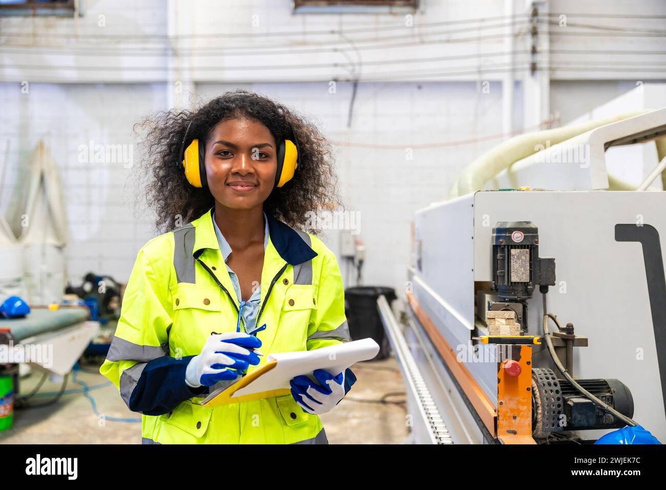 Le lavoratrici nere africane lavorano con l'industria della fabbrica di mobili della taglierina del legno con tuta di sicurezza Foto Stock
