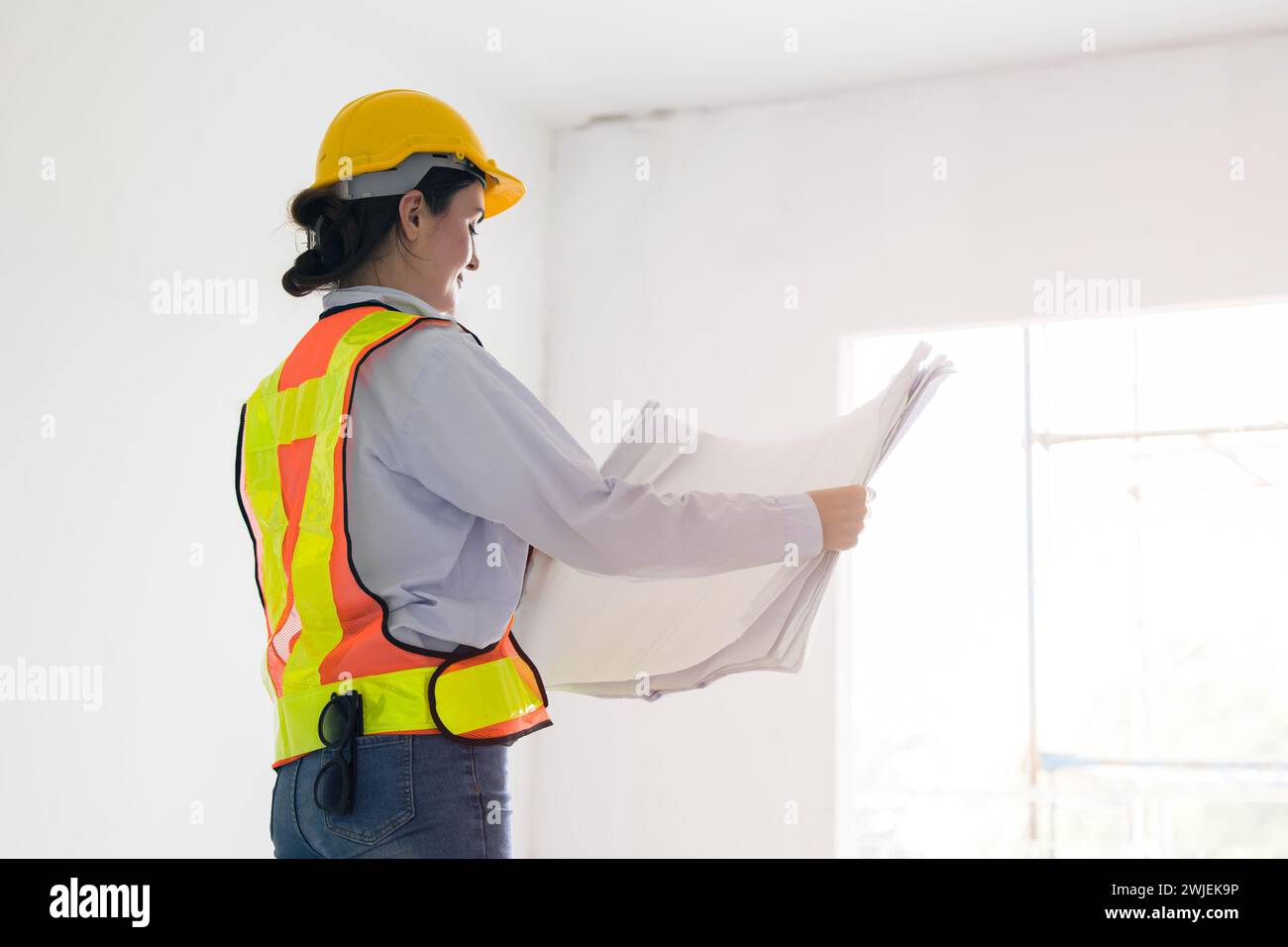 Giovani donne lavoratrici intelligenti ingegnere edile costruttore donna caucasica architetto che guarda pianta in progetto di costruzione in cantiere Mana Foto Stock