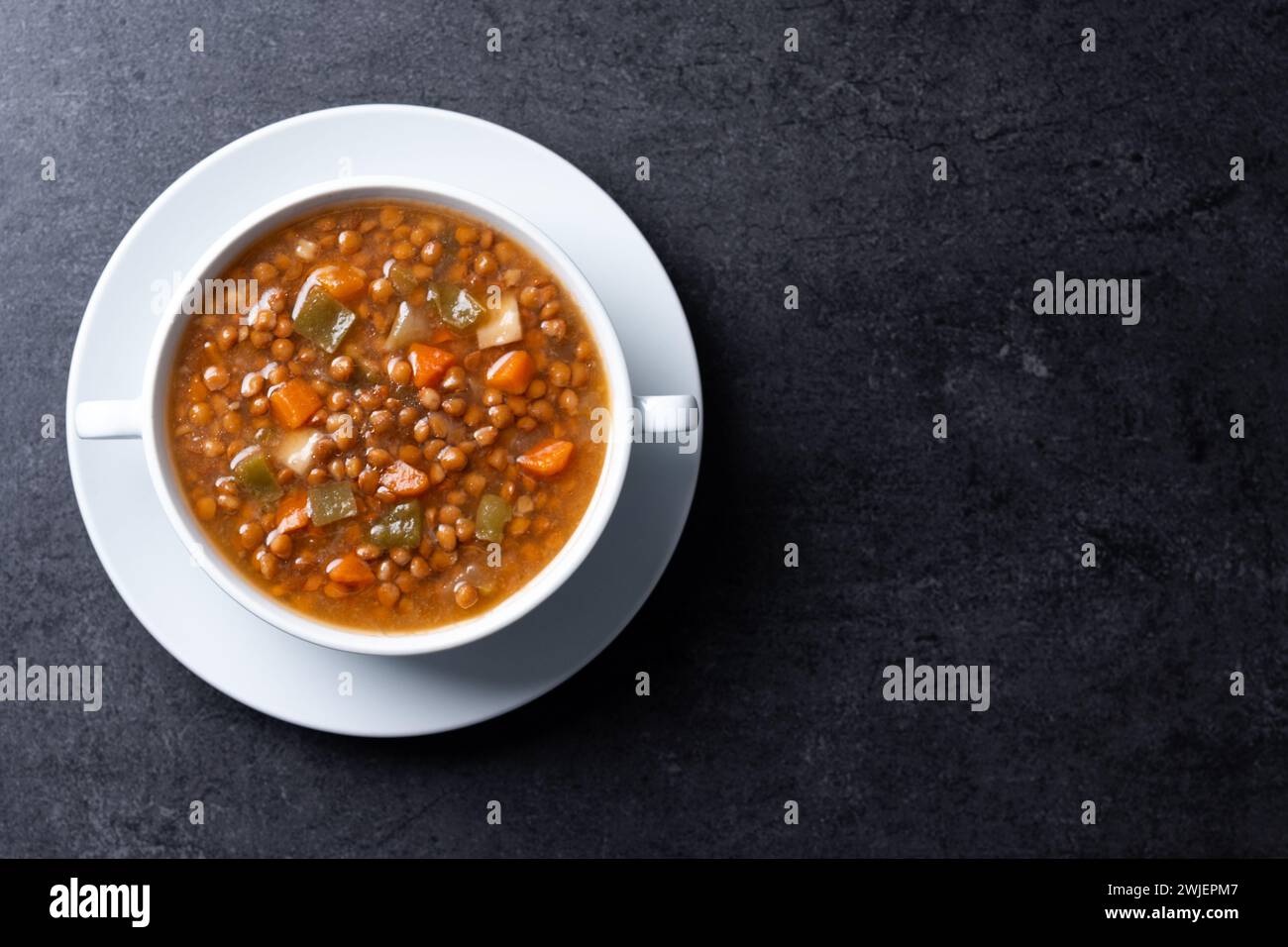 Zuppa di lenticchie con verdure nel recipiente su sfondo nero Foto Stock