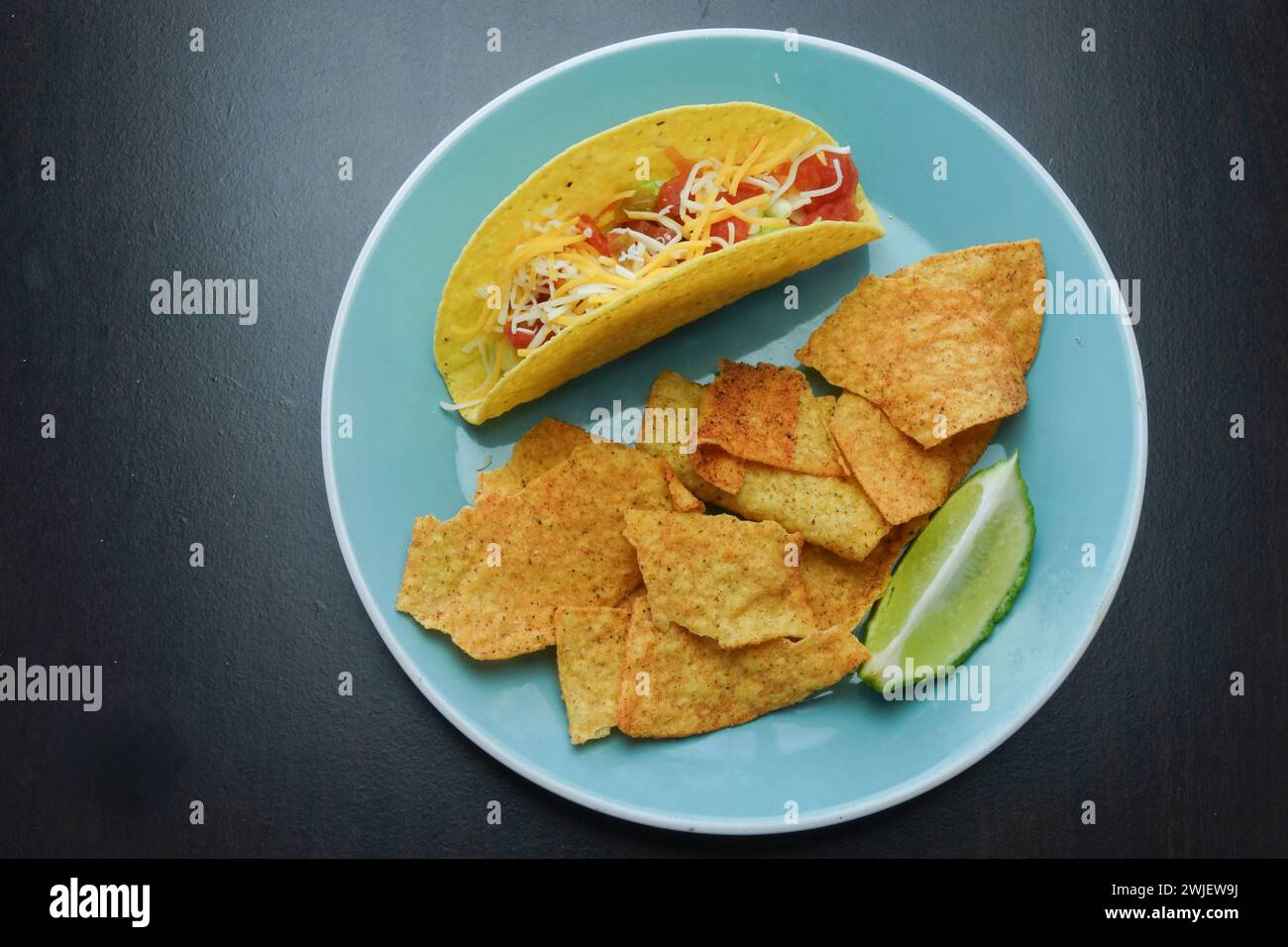 Un delizioso taco e patatine croccanti servite su un vivace piatto blu Foto Stock