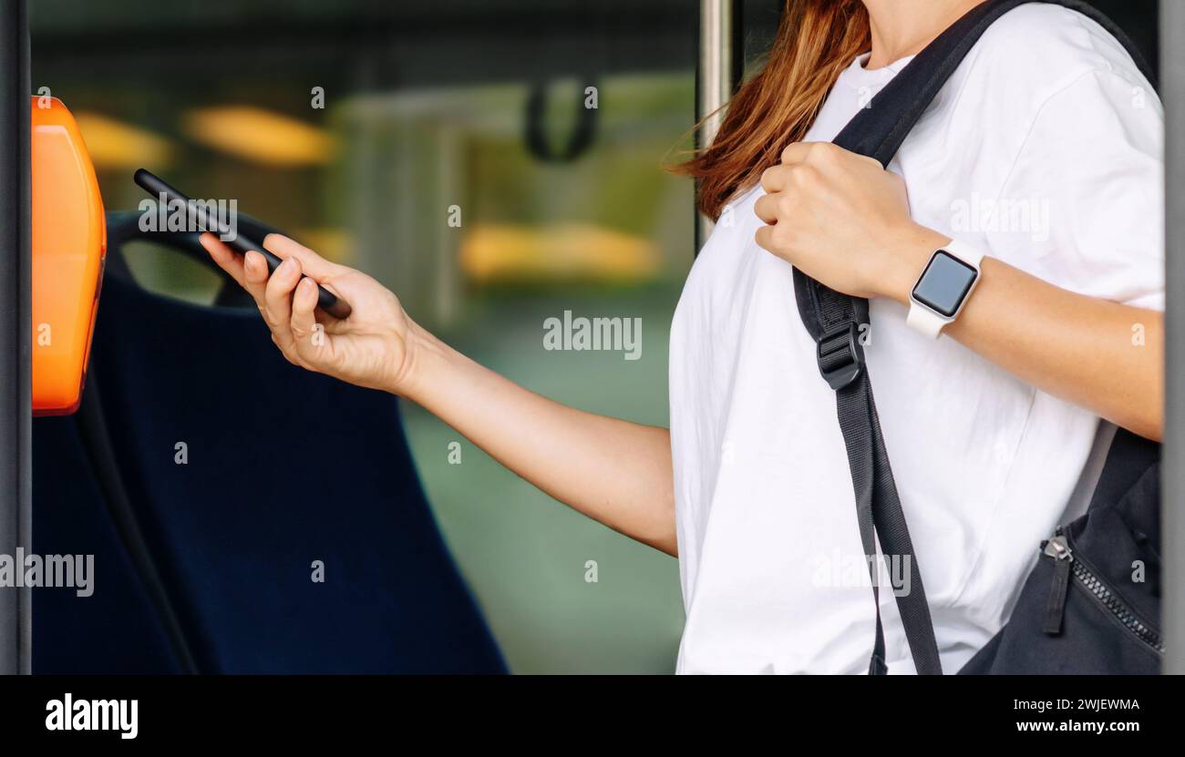 Passeggero donna che paga il biglietto dell'autobus con il suo smartphone. Foto Stock