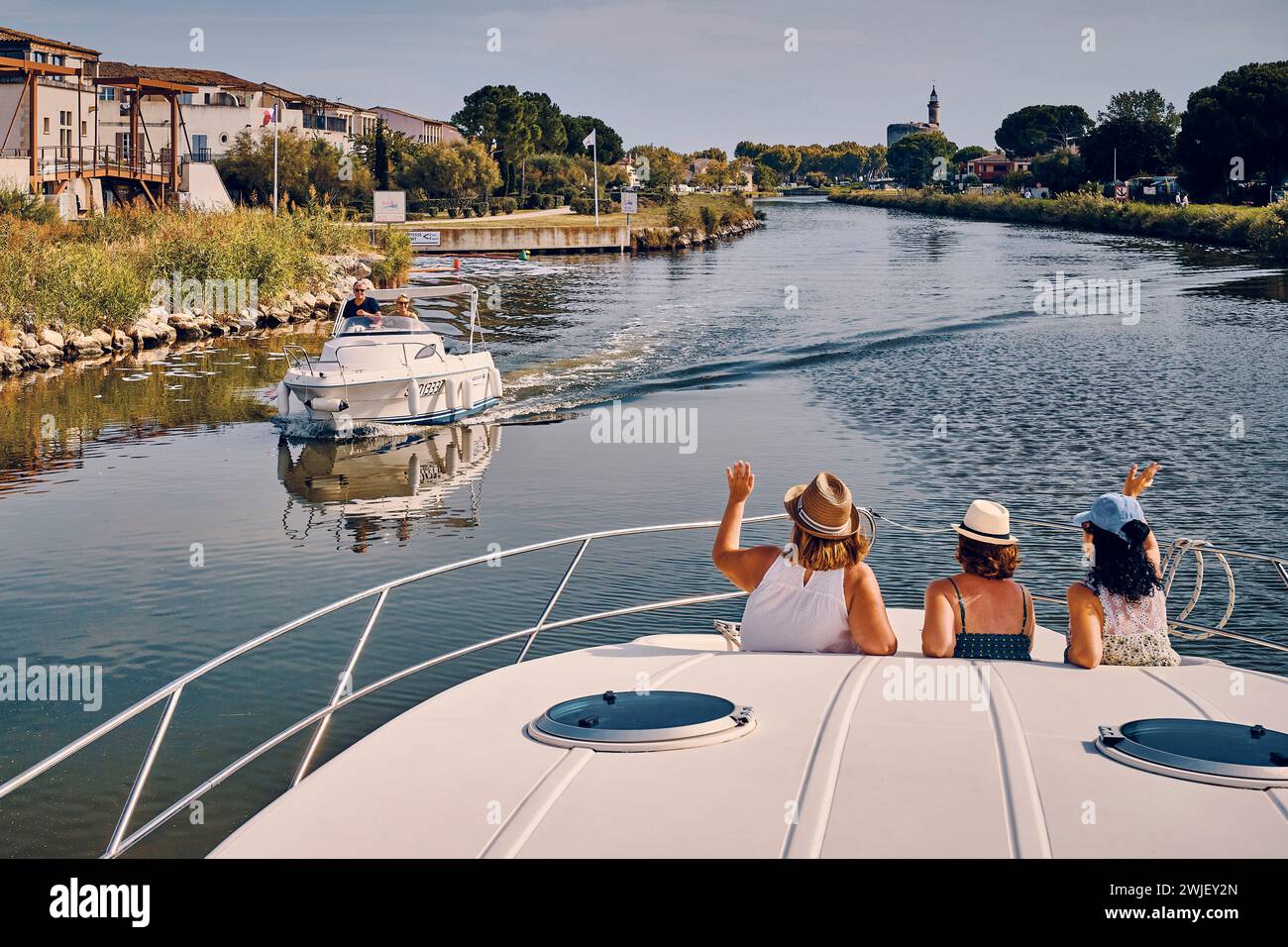 Aigues-Mortes (sud della Francia): Turismo sul “Canal du Rhone a Sete” (canale Rodano-Sete). Tre donne viste da dietro su una chiatta a noleggio che ondeggiava come Foto Stock