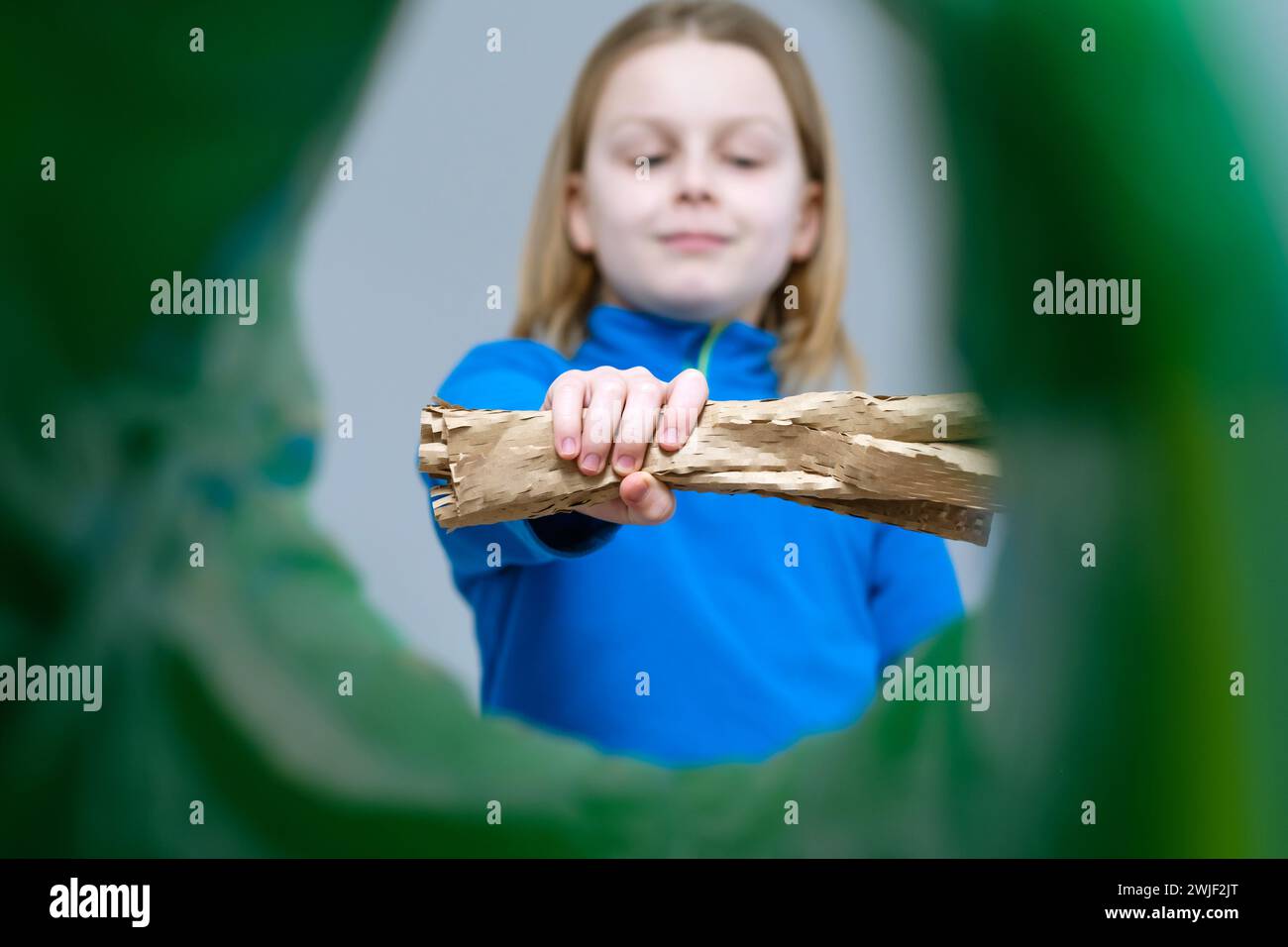 Carta marrone arrotolata per bambini con vista bassa o confezione regalo confezionata in un contenitore dei rifiuti, concetto di riciclaggio e smistamento dei rifiuti. Foto Stock