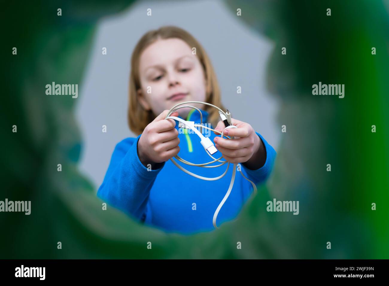 Mani con vista ad angolo basso smistamento maschio rifiuti elettronici più vicini nel cestino domestico. Riciclaggio dei fili elettrici. Foto Stock