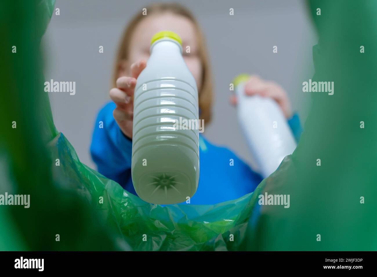 Visualizzazione ad angolo basso del cestino di smistamento dei bambini in plastica in casa. Smaltimento dei prodotti in bottiglia di latte. Società sostenibile e rispettosa dell'ambiente a pr Foto Stock