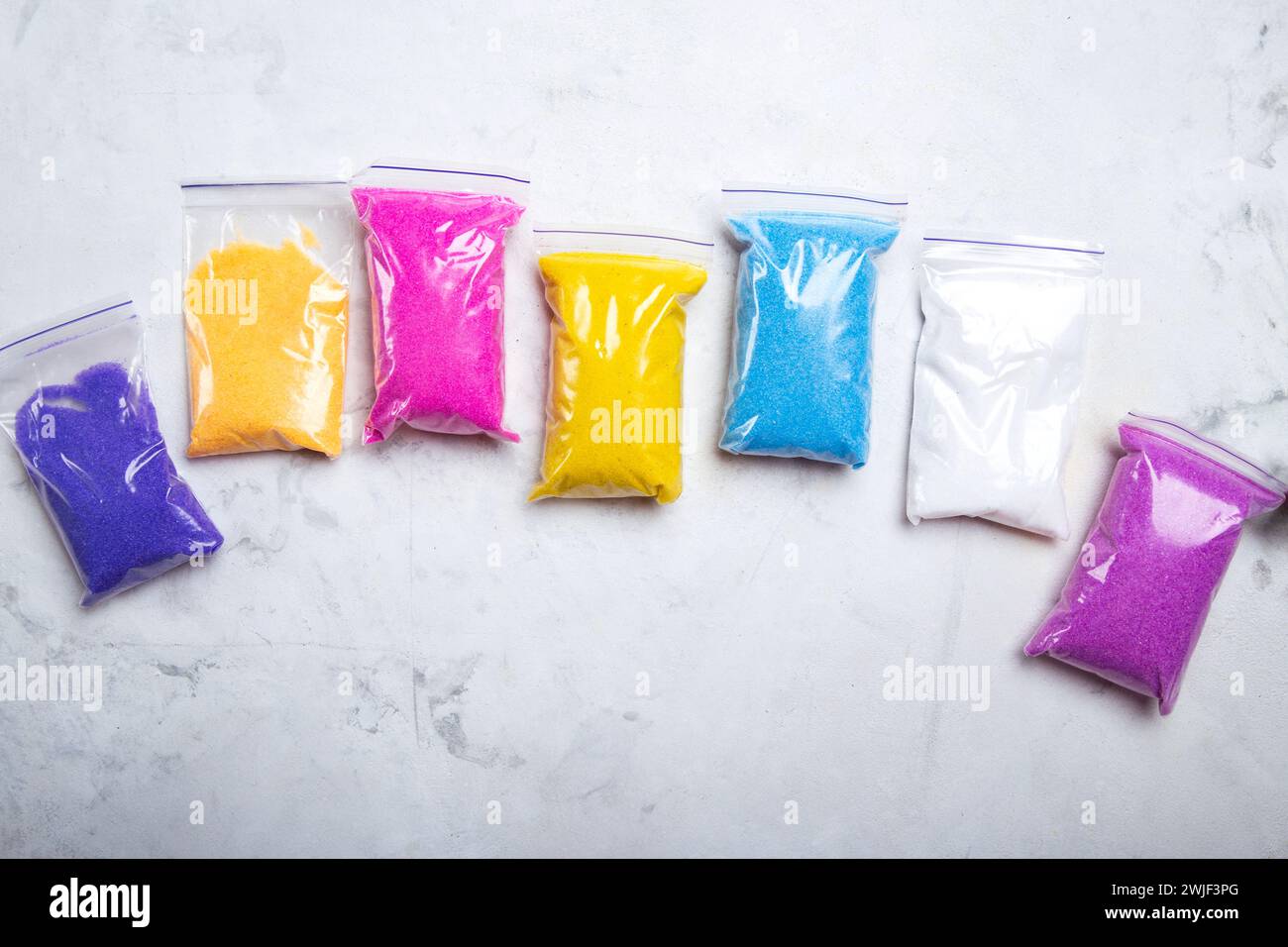 Colori arcobaleno di materiali abrasivi in imballaggi in plastica su superficie ruvida Foto Stock