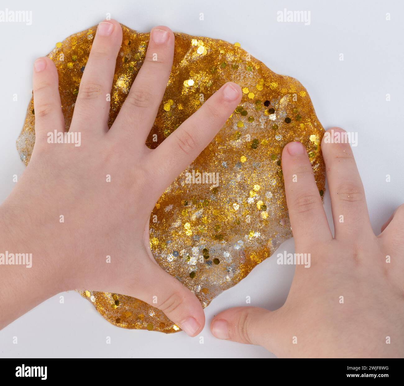 I bambini giocano con la vista ravvicinata Slime macro color oro isolata Foto Stock