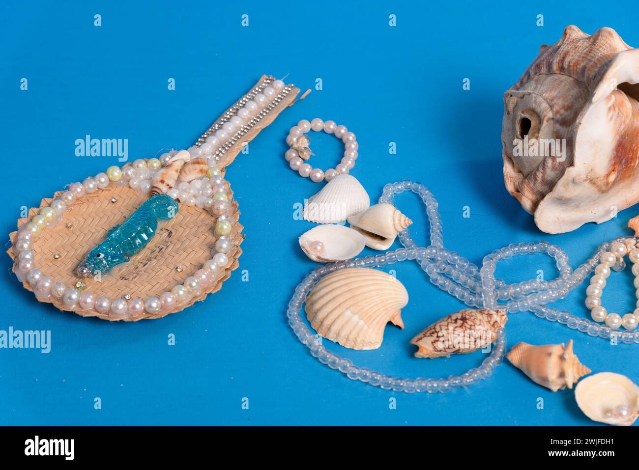 Diverse conchiglie marine, collane e specchi sparsi sul piano blu dello studio. Omaggio a iemanja. Foto Stock