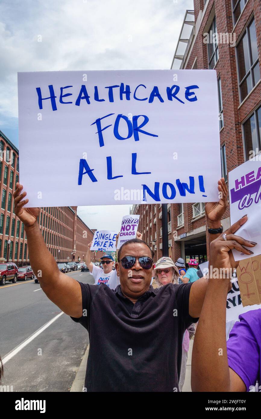 LAWRENCE, ma, Stati Uniti – 20 LUGLIO 2017: Ispanico tiene in piedi un cartello di protesta con la scritta "Healthcare for All". Foto Stock