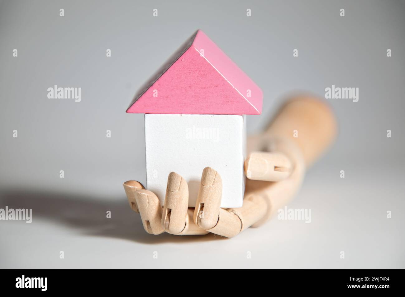 Modello che tiene a mano i blocchi giocattolo a forma di un hous, concetto di immobili e costruzione di case Foto Stock