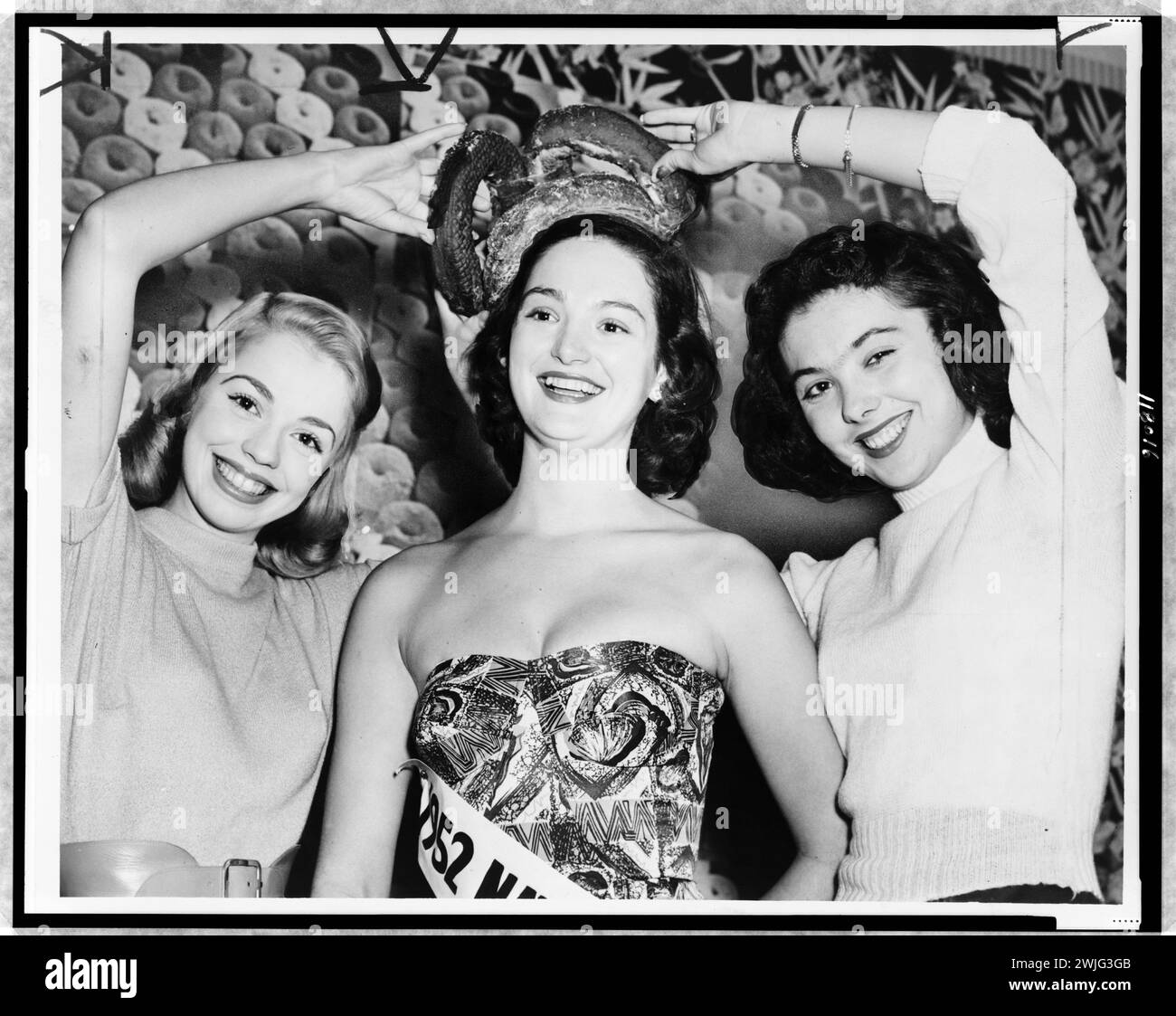 Diane Scholen (a sinistra) e Pat Kizeminski (a destra) (secondi classificati), posiziona la corona di ciambella su Nancy Templeton, National Doughnut Queen, New Yok, NY, circa 1952. (Foto di Fred Palumbo/World Telegram & Sun) Foto Stock