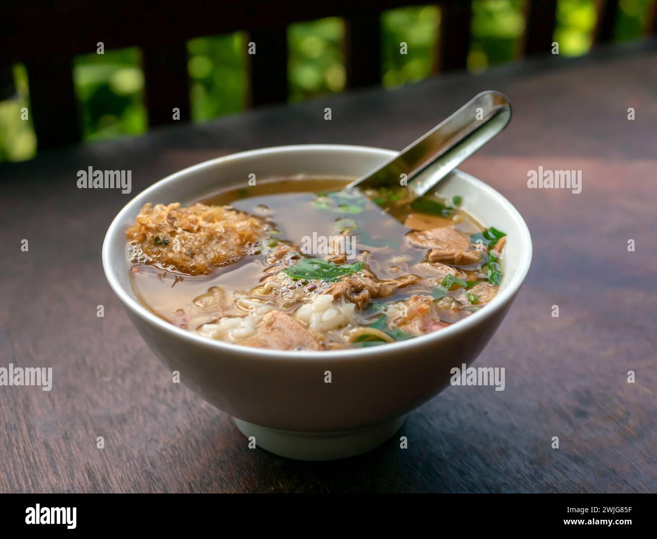 Soto Ayam, una tradizionale zuppa di pollo indonesiana su un tavolo di legno. Foto Stock