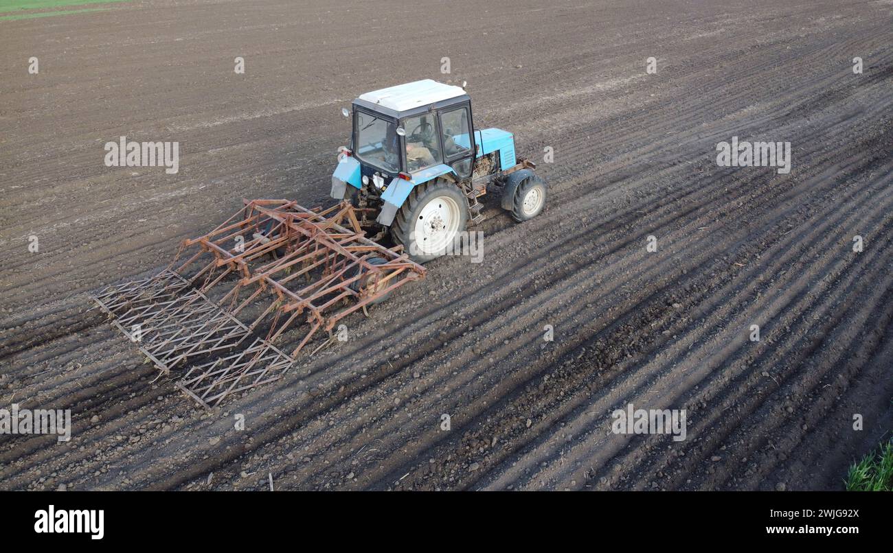 Agricoltore nel trattore che prepara terreni con coltivatore a seminale a primavera Foto Stock