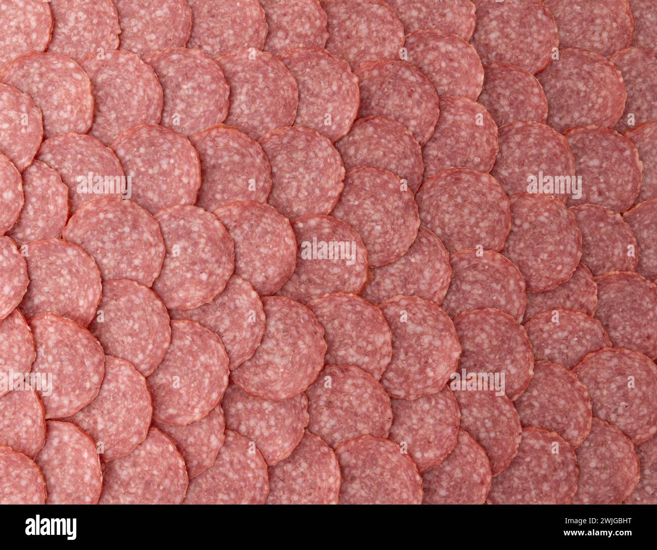salame a fette di salsiccia come sfondo, pezzetti di salsiccia di prosciutto a fette da vicino Foto Stock