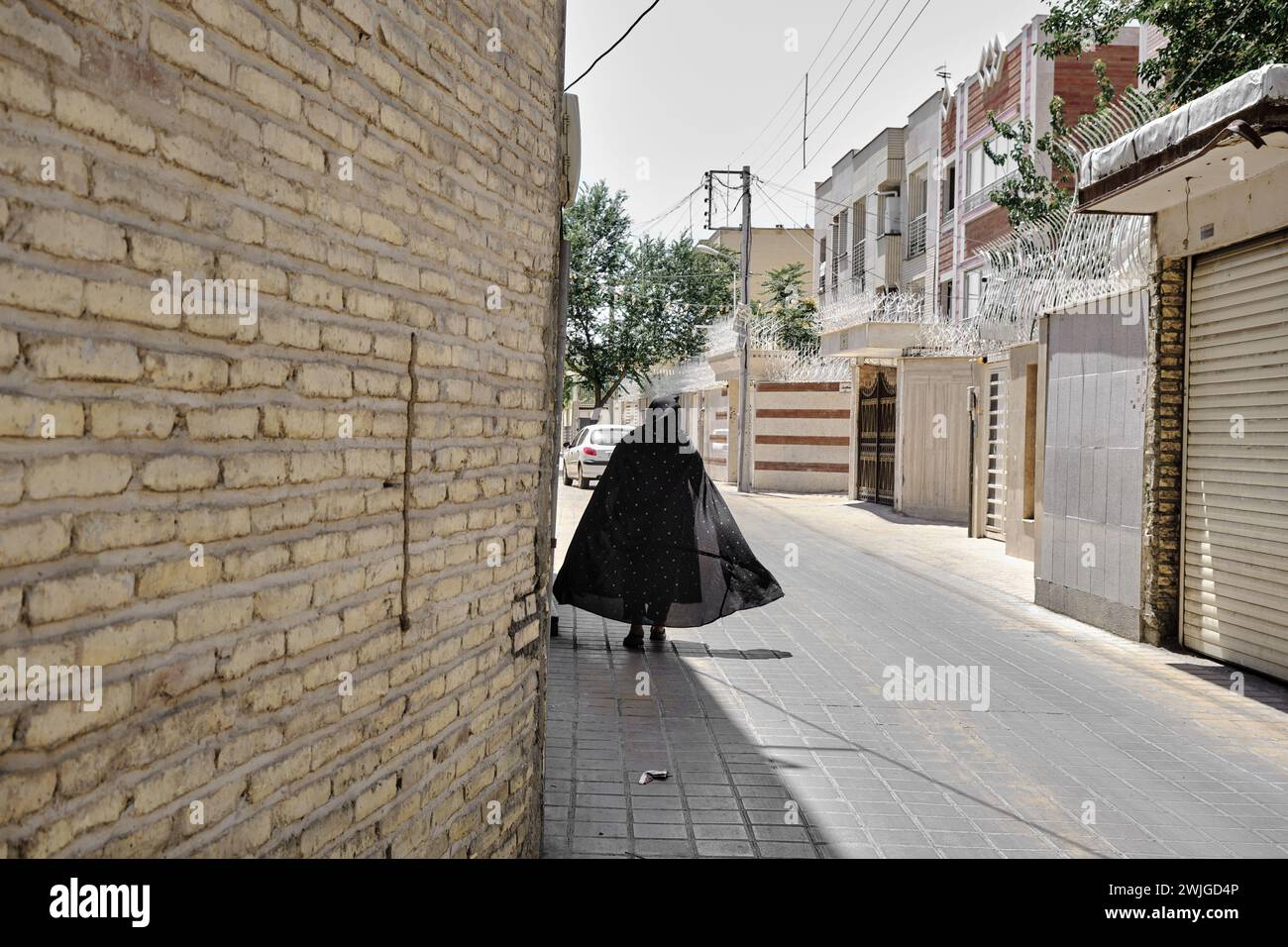 Isfahan, Iran, 06.30.2023: Un'anziana donna che cammina in strada iraniana, donna nel tradizionale burqa nero iraniano Foto Stock