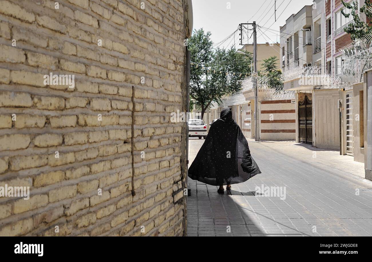 Isfahan, Iran, 06.30.2023: Un'anziana donna che cammina in strada iraniana, donna nel tradizionale burqa nero iraniano Foto Stock