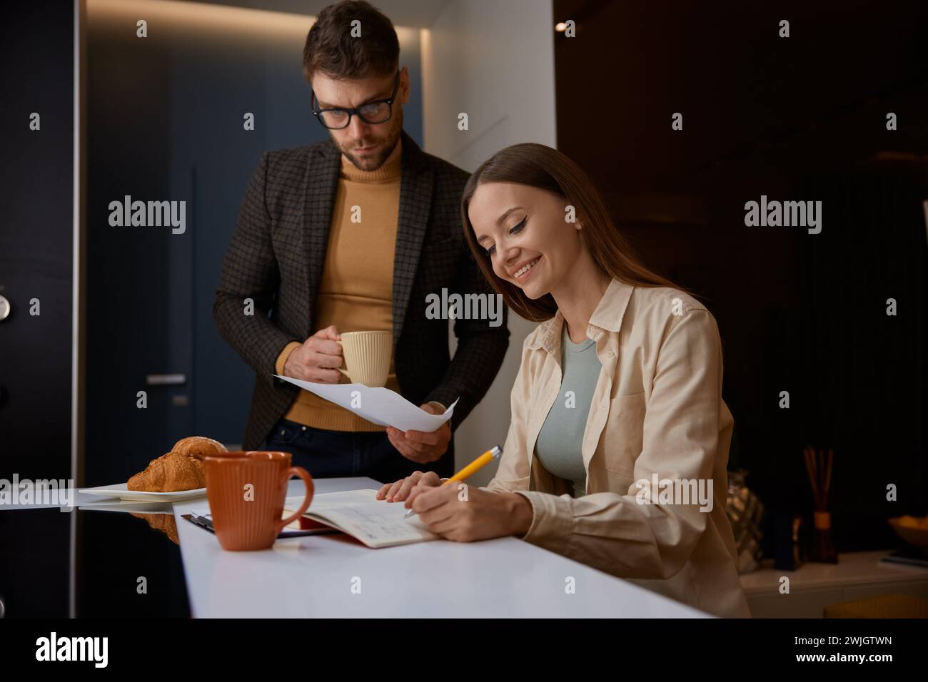 Un marito serio che tiene in mano la carta e chiede alla moglie dei costi aggiuntivi Foto Stock