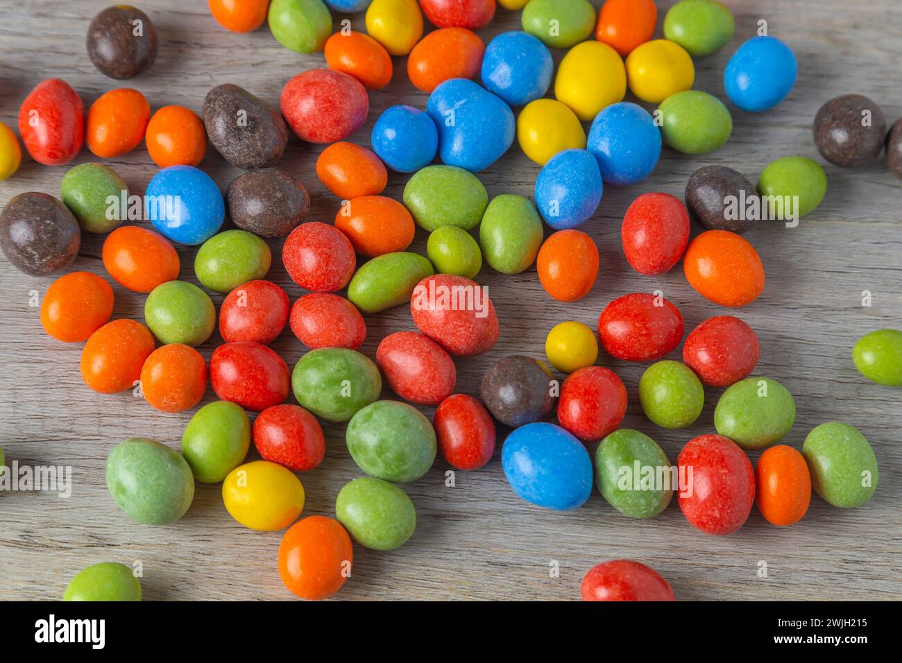 Arachidi in glassa multicolore al cioccolato su un tavolo di legno. Vista dall'alto. Foto Stock