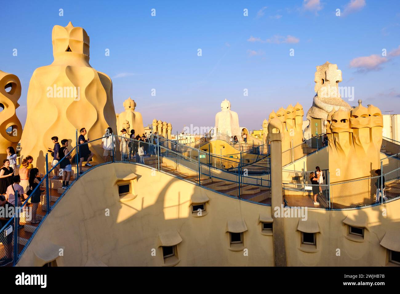 Tetto di Casa Milà, la Pedrera, turisti sul tetto, camini e sfiati al tramonto, architettura modernista di Antoni Gaudí, Barcellona, Spagna Foto Stock