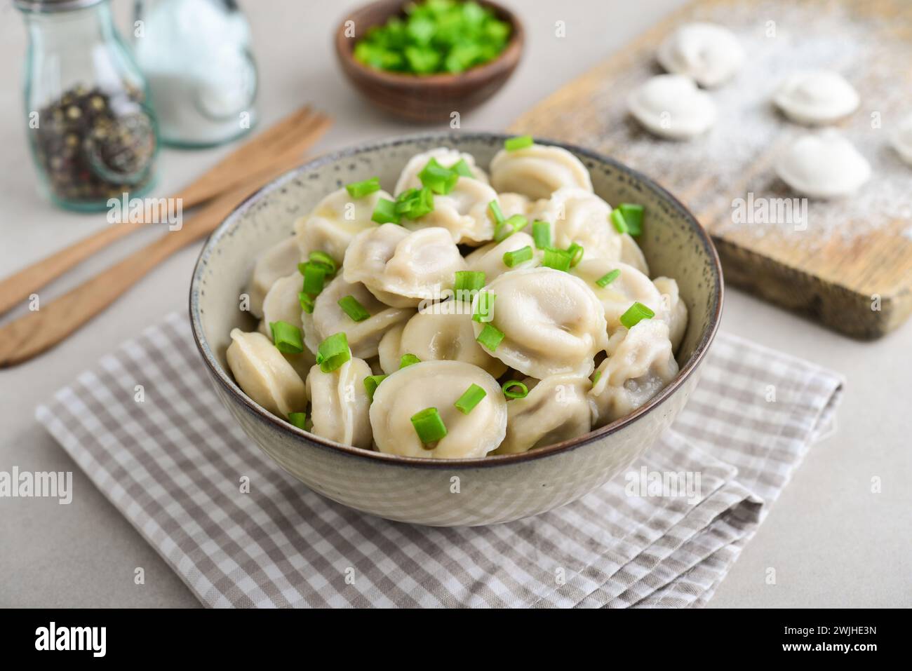 Pelmeni russi, gnocchi con carne, burro ed erbe aromatiche su uno sfondo chiaro Foto Stock