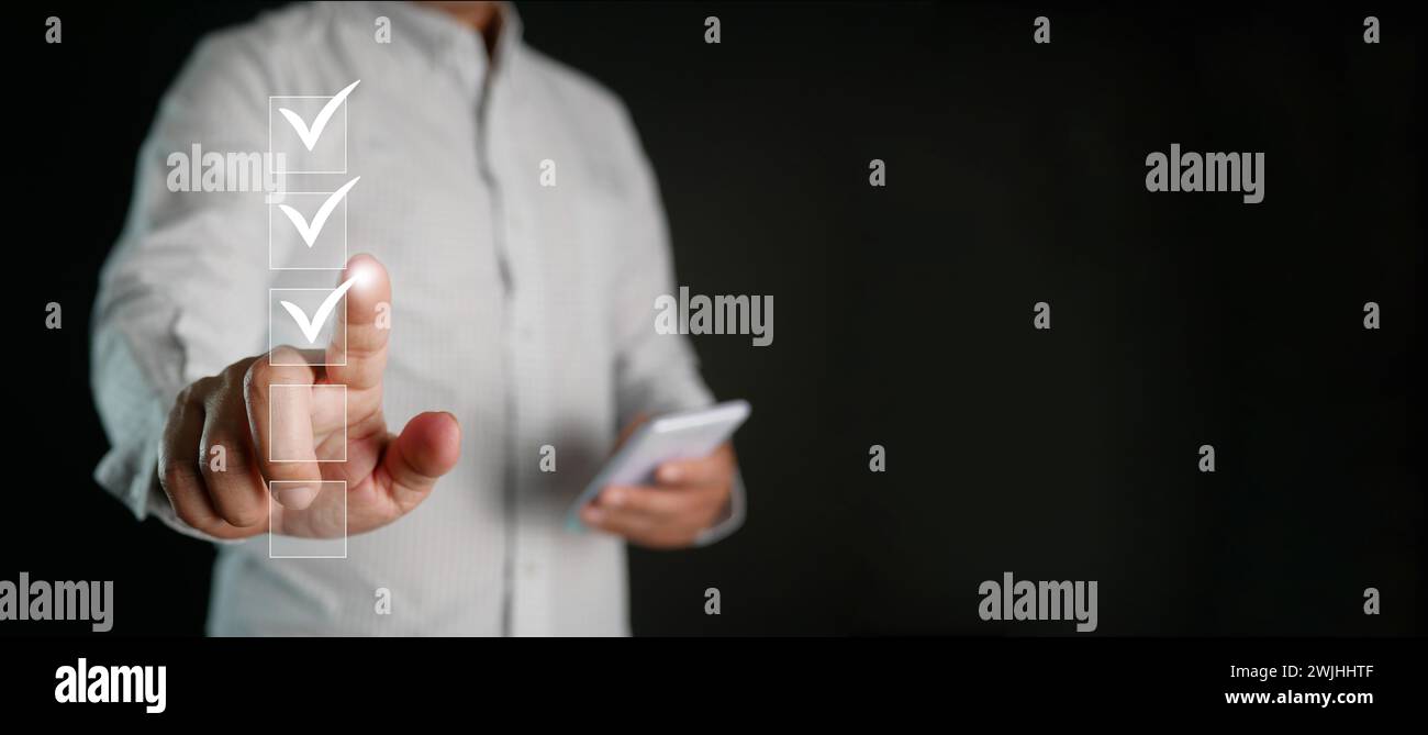 Informazioni sulla lista di controllo. Un uomo che controlla i segni digitali corretti sulle caselle di controllo. Monitoraggio intelligente delle prestazioni, compilazione del sondaggio online, modulo elettronico per smartphone Foto Stock