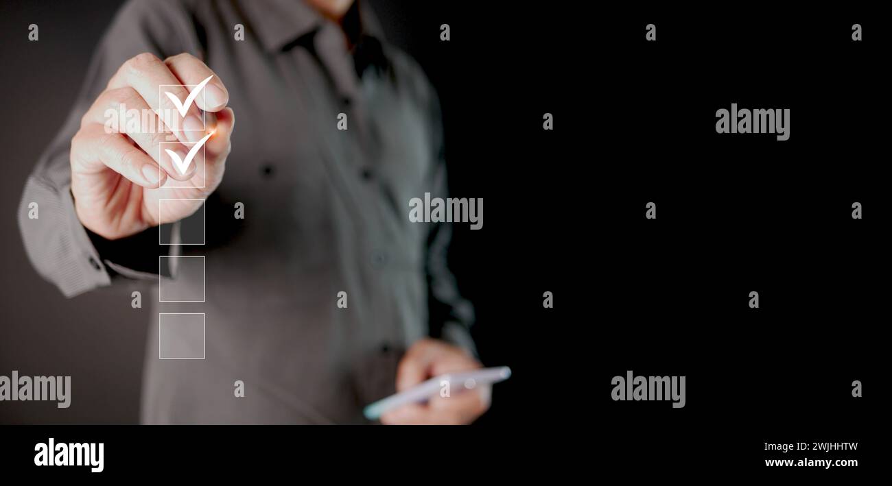 Informazioni sulla lista di controllo. Un uomo con stilo che controlla i segni digitali corretti sulle caselle di controllo. Monitoraggio intelligente delle prestazioni, compilazione del sondaggio online, smartphone Foto Stock